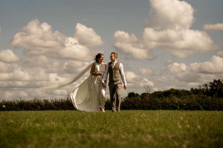 Bride and groom walking across a field