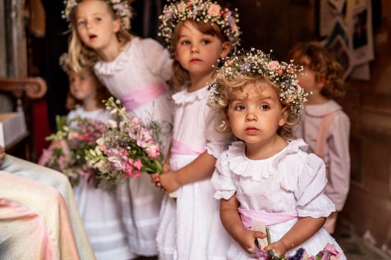 Flower girls look at bride arriving at church