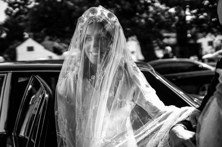 Bride smiling as she leaves the wedding car 