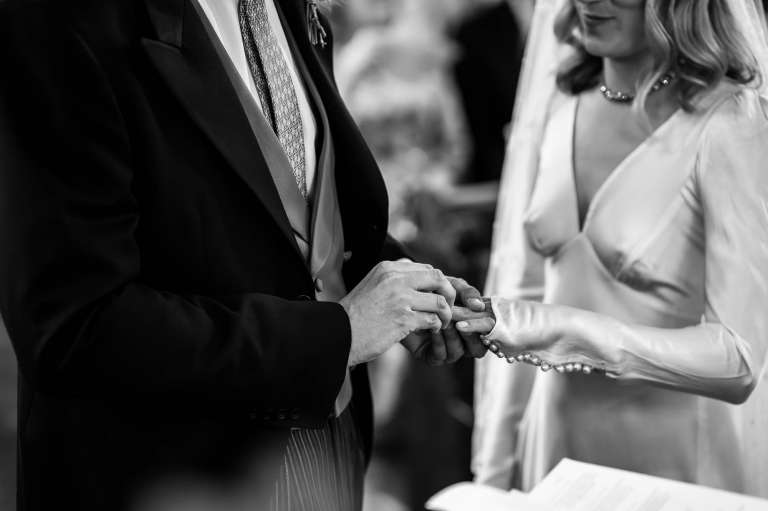 Close up of groom placing ring on brides finger