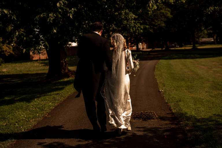 Bride and groom walk towards Meols Hall