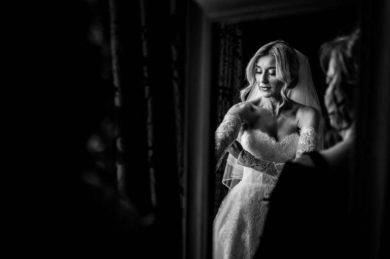 Reflection of the bride in the mirror putting on her wedding dress.