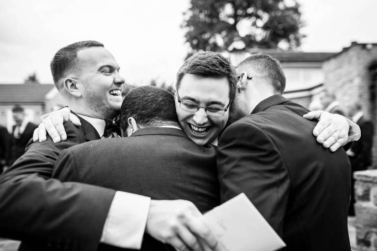 The groom gets a group hug during the drinks reception